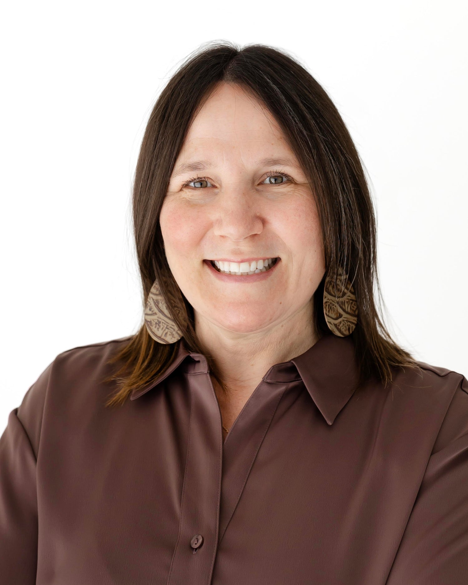 Headshot of Sarah Kinlin wearing a brown shirt with a plain background
