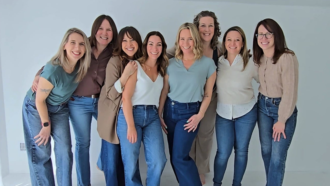 Group of women posing together in a white room